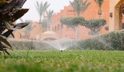 modern device of irrigation garden irrigation system technique of watering in the garden lawn sprinkler spraying water over green grass photo
